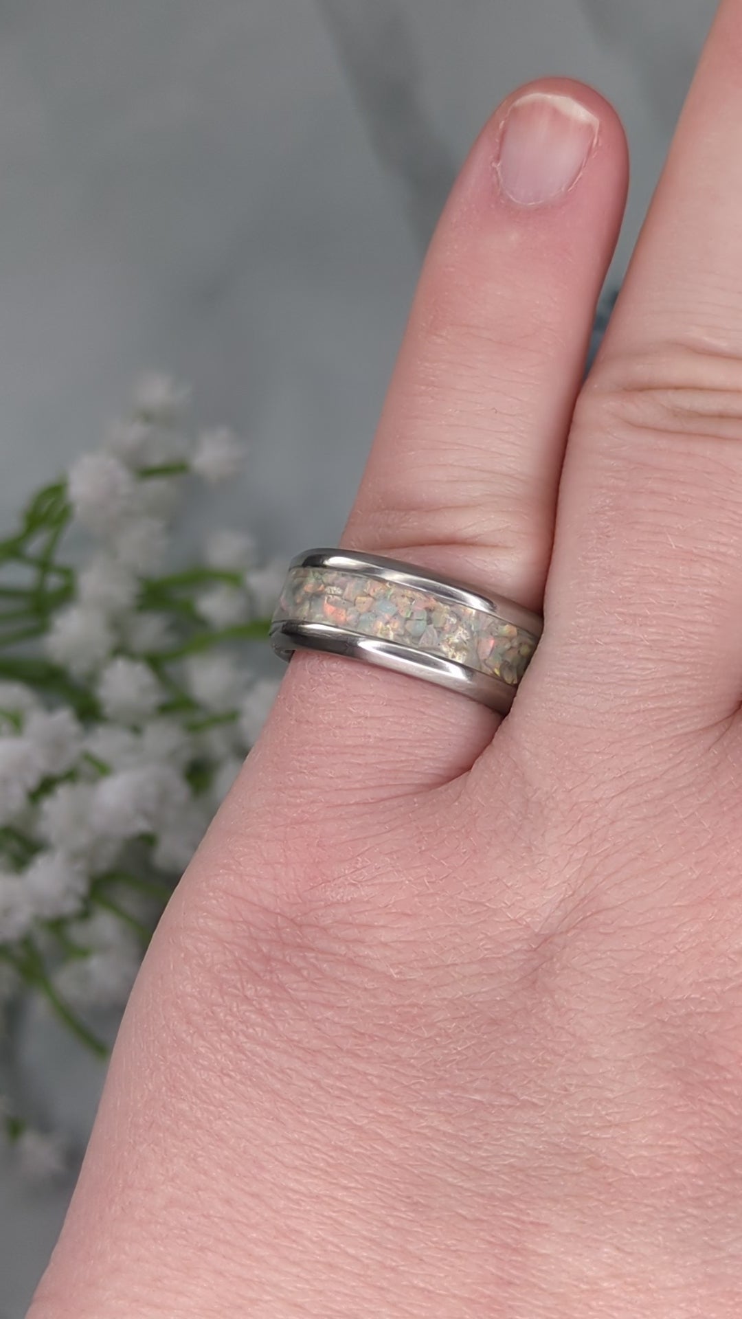 Rainbow-hued white fire and ice opal in a stainless steel inlay channel ring. The ring is on a finger and rotated in the video.