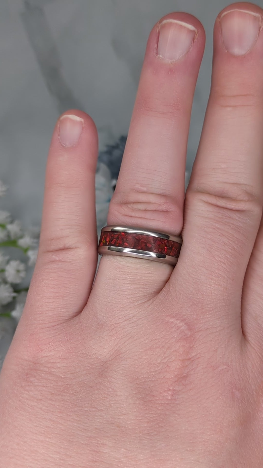 Vibrant red fire opal in a stainless steel inlay channel ring. The ring is on a finger and rotated in the video to show the shine and sparkle.